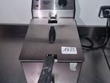 une photo d'une friteuse professionnelle posée sur un plan de travail en inox