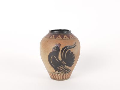 un petit vase avec un oiseau sur une surface blanche