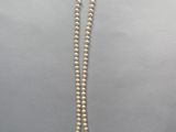 un collier de perles blanches avec un fermoir en or sur fond blanc
