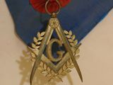 a medal with a red ribbon and a pair of scissors hanging from it