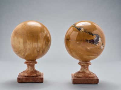 paire de globes en marbre sculpté reposant sur des socles en bois
