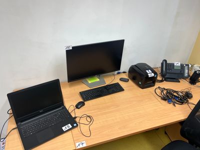 un bureau sur lequel se trouvent un ordinateur portable, un téléphone et d'autres appareils électroniques