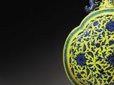 yellow and blue vase with blue flowers on it with a black background