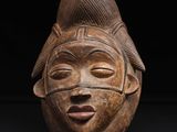 un gros plan d'un masque en bois posé sur une surface noire