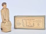 une petite statue en bois représentant un homme assis sur une caisse