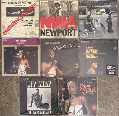 various vinyl records on the floor of a room with a wall full of them