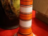 un bougeoir rayé orange et blanc posé sur une table rouge