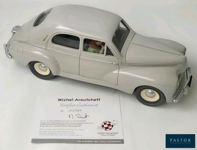 une petite voiture en argent avec un homme au volant