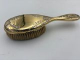 an antique brass plated brush with a handle and handle on a white surface