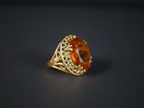 une bague en or sertie d'une pierre orange entourée de filigrane