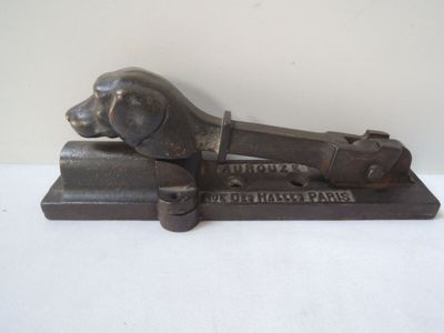 un objet métallique sur lequel figure un chien, posé sur une surface blanche