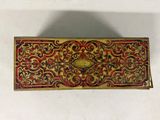 a close up of a gold and red box on a white surface