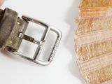 a person holding a belt with a shell in the background