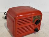 une vieille radio rouge posée sur une table blanche