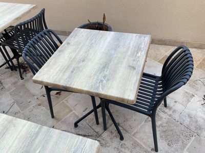 une table et des chaises sur une terrasse, avec un chat assis dessus
