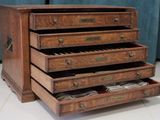 a wooden chest of drawers that has a bunch of papers in it