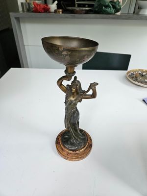 a statue of a woman holding a bowl on top of a table