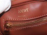 a person holding a brown purse with a gold zipper