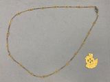 un collier en or et une pièce d'or posés sur une surface grise