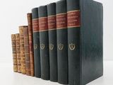 five old books are lined up on a white surface