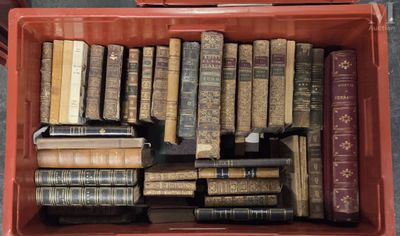 de nombreux livres anciens dans une boîte rouge posée par terre