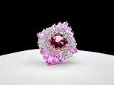 a close up of a pink and white diamond ring on a white surface