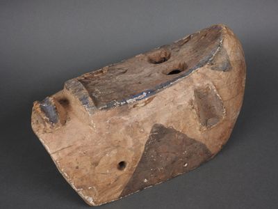 un objet en forme de vieux bateau en bois posé sur une surface grise