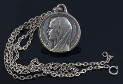 an image of a silver coin with a chain on a black surface