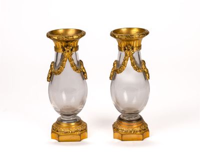 pair of gold and clear glass vases sitting on top of a wooden stand