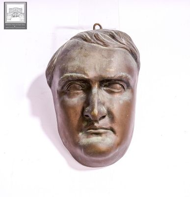 une tête d'homme en bronze sur un mur blanc