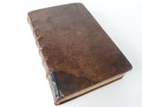 an old brown book sitting on top of a white table