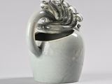a white vase with a plant in it sitting on a table