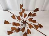 un gros plan d'une sculpture métallique représentant des feuilles sur une surface blanche