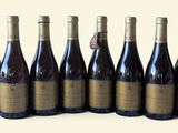 six bouteilles de vin sont alignées sur une surface blanche