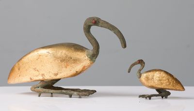 paire d'oiseaux en bronze posés sur un socle, sur une surface blanche avec un fond gris