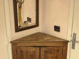 une petite armoire d'angle avec un miroir accroché au mur