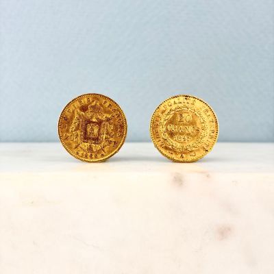 deux pièces d'or posées sur un plan de travail en marbre