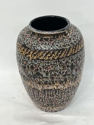 un vase noir et or posé sur une surface blanche