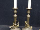 pair of antique brass candlesticks with candles on each side
