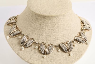 Collier doré orné de breloques en forme de cœur et de perles, présenté sur un mannequin