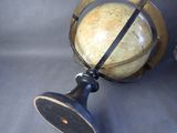a globe on a stand on a gray surface