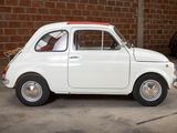 a small white car parked in front of a brick wall