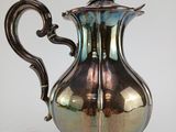 an antique silver plated coffee pot on a white background