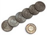 several coins are shown next to a penny on a white surface