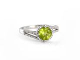 a close up of a ring with a green stone surrounded by diamonds