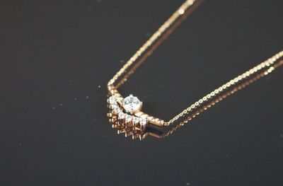 un gros plan d'un collier en or orné de deux diamants, sur un fond noir