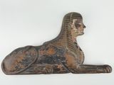 statue d'un sphinx couché sur une surface blanche, avec un fond blanc