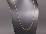 un collier à chaîne en or posé sur un présentoir noir pour mannequin