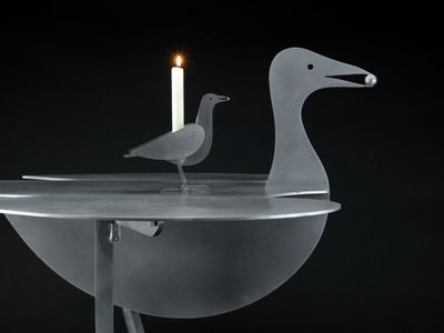 a bird that is sitting on a table with a candle