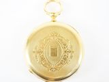 une image représentant une montre de poche en or sur laquelle figure un blason